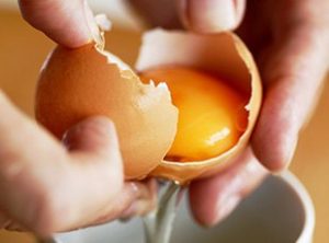 Someone cracking open a brown egg