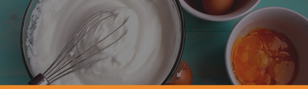 a whisk is in a bowl of whipped cream next to two bowls of eggs
